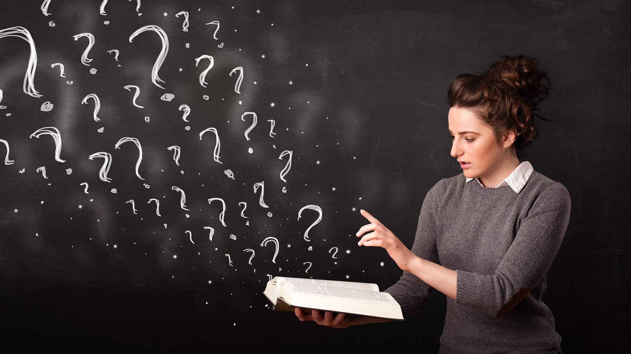 A woman holding an open book that has many different sized questions marks coming out of the book