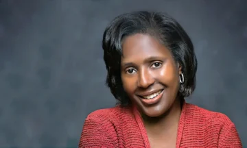 A headshot of Lynn Wooten standing in front of a bluish-gray background.
