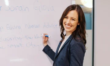 Sarah Glova writing on a whiteboard with a dry erase marker.