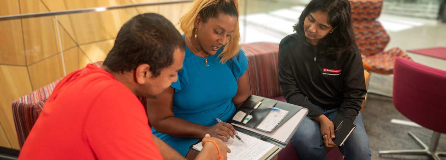 Latha Dombro, student services coordinator, sitting on a couch with two MEM Students discussing their schedules