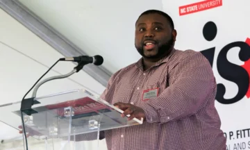 A headshot of Devon Person standing at a podium.