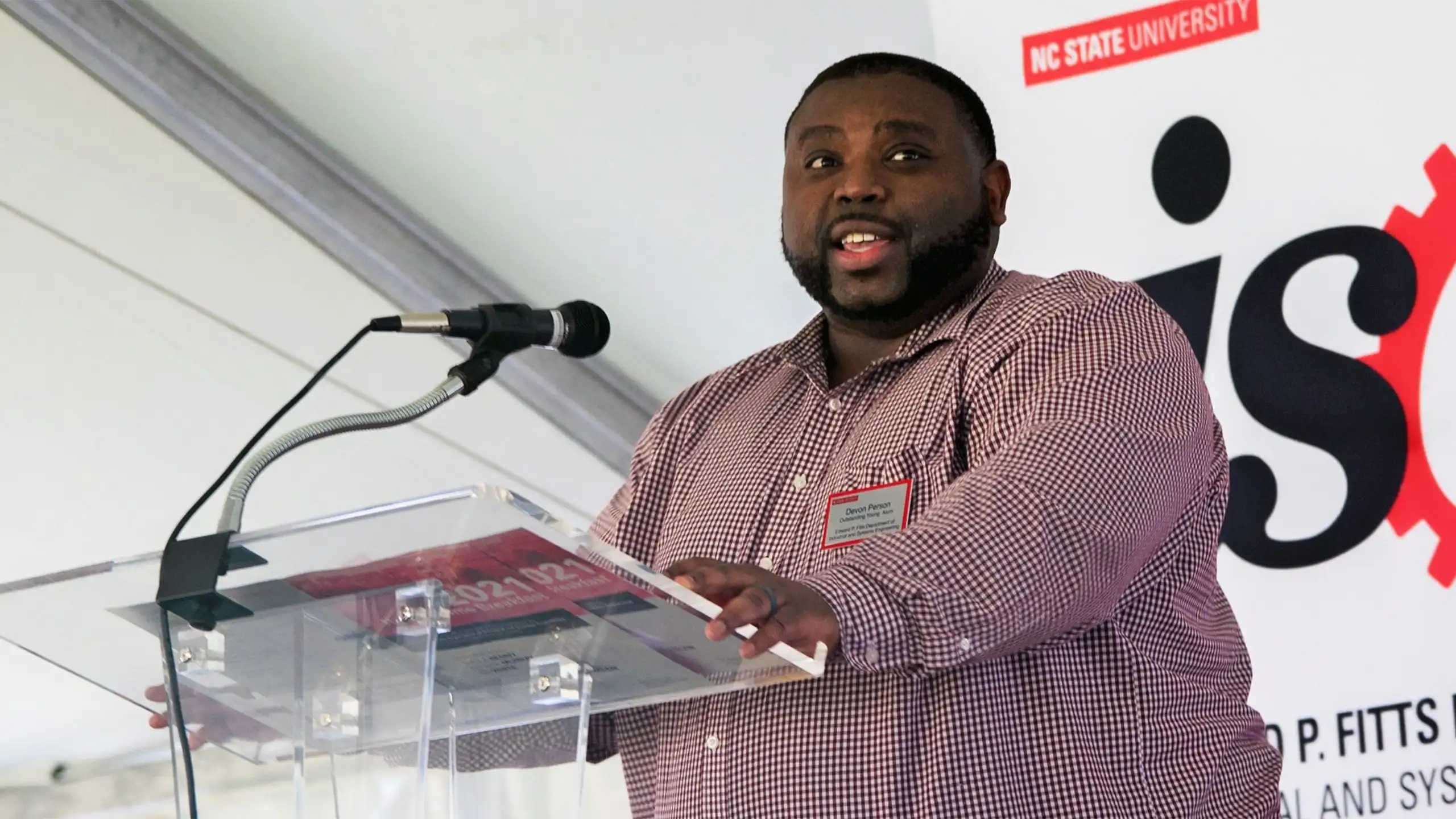 A headshot of Devon Person standing at a podium.