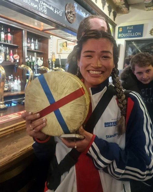 Lampe holds up her trophy, a 7 - 9 pound wheel of Double Gloucester Cheese