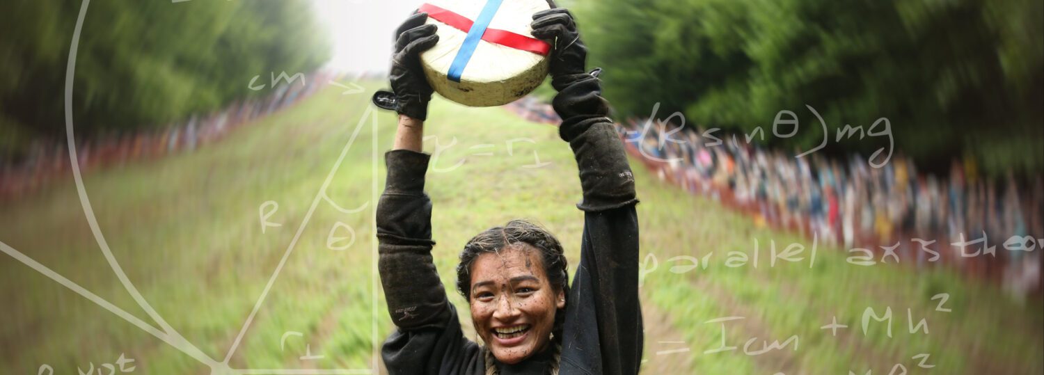 Abby Lampe raising the wheel of cheese over her head at the bottom of Cooper's Hill