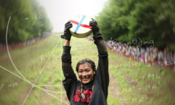 Abby Lampe raising the wheel of cheese over her head at the bottom of Cooper's Hill