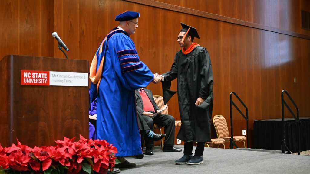 As MEM student Kartik Khanderia walks onto the stage he shakes hands with the professor Russell King