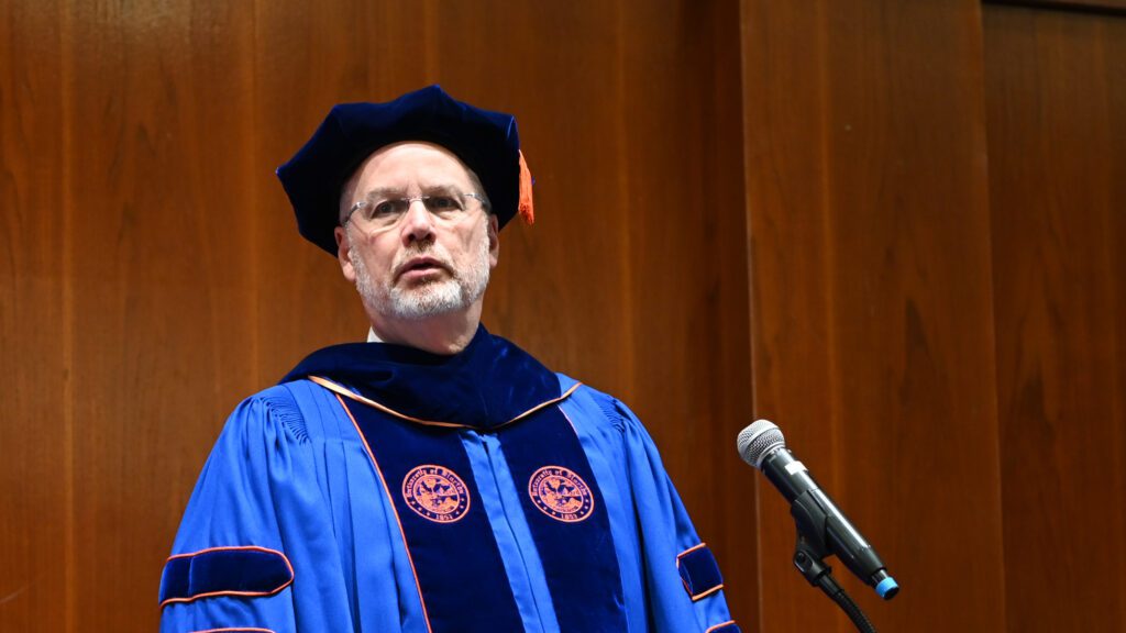 From behind the podium, professor Russell King calls each MEM student's name