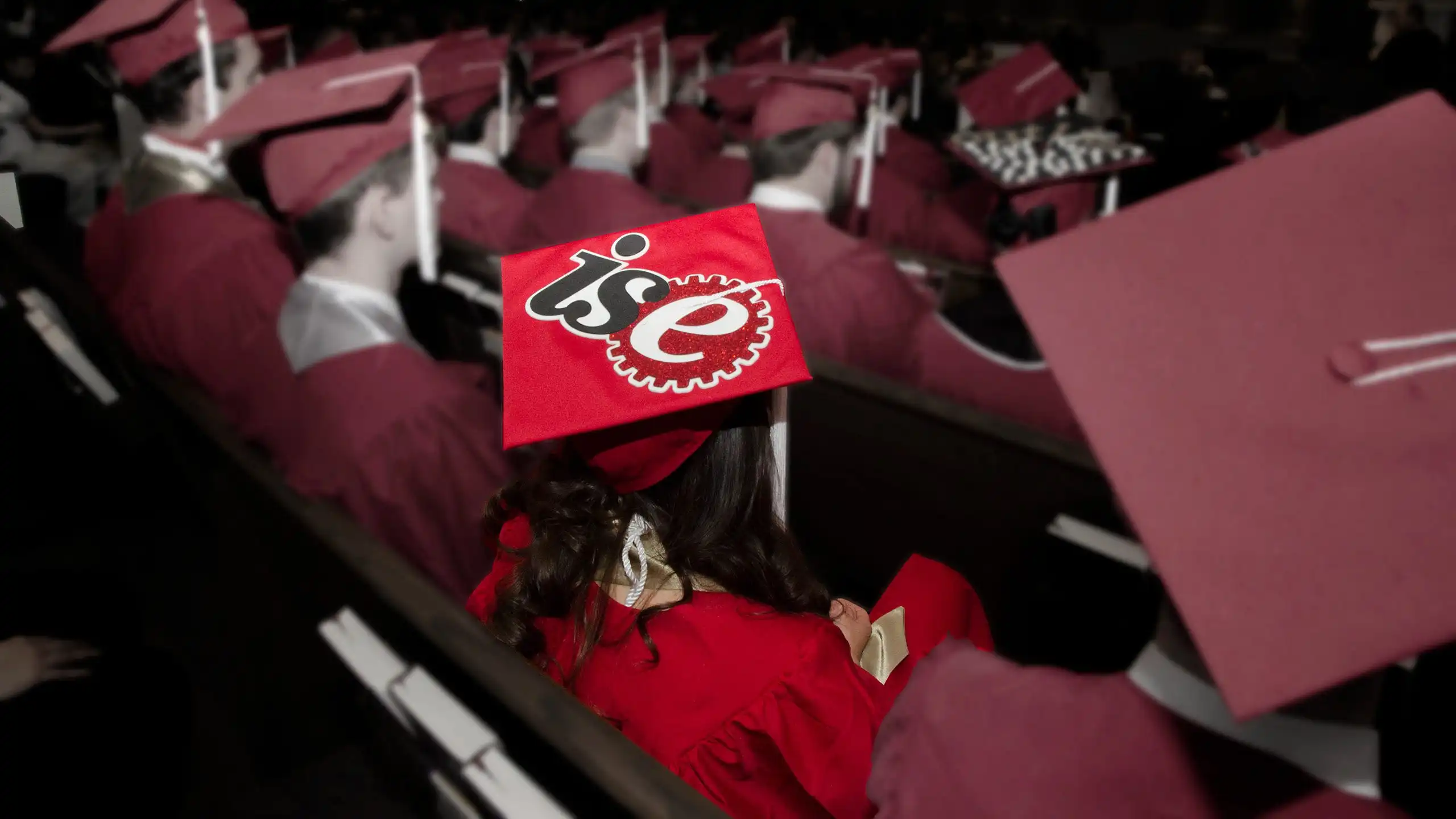 Rows of students at graduation with one student highlighted.