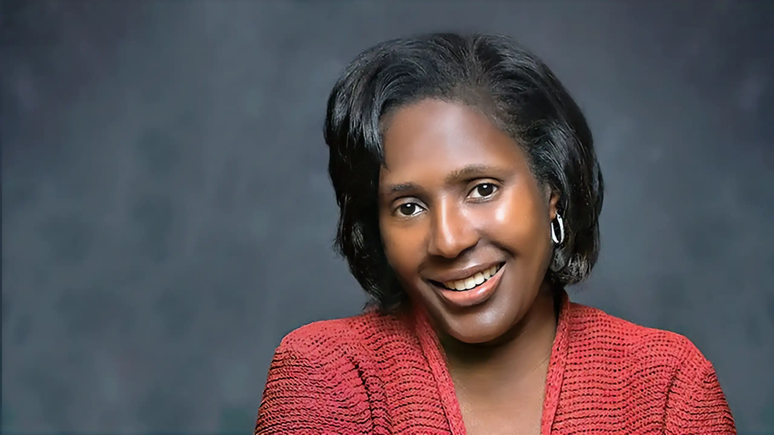 A headshot of Lynn Wooten standing in front of a bluish-gray background.