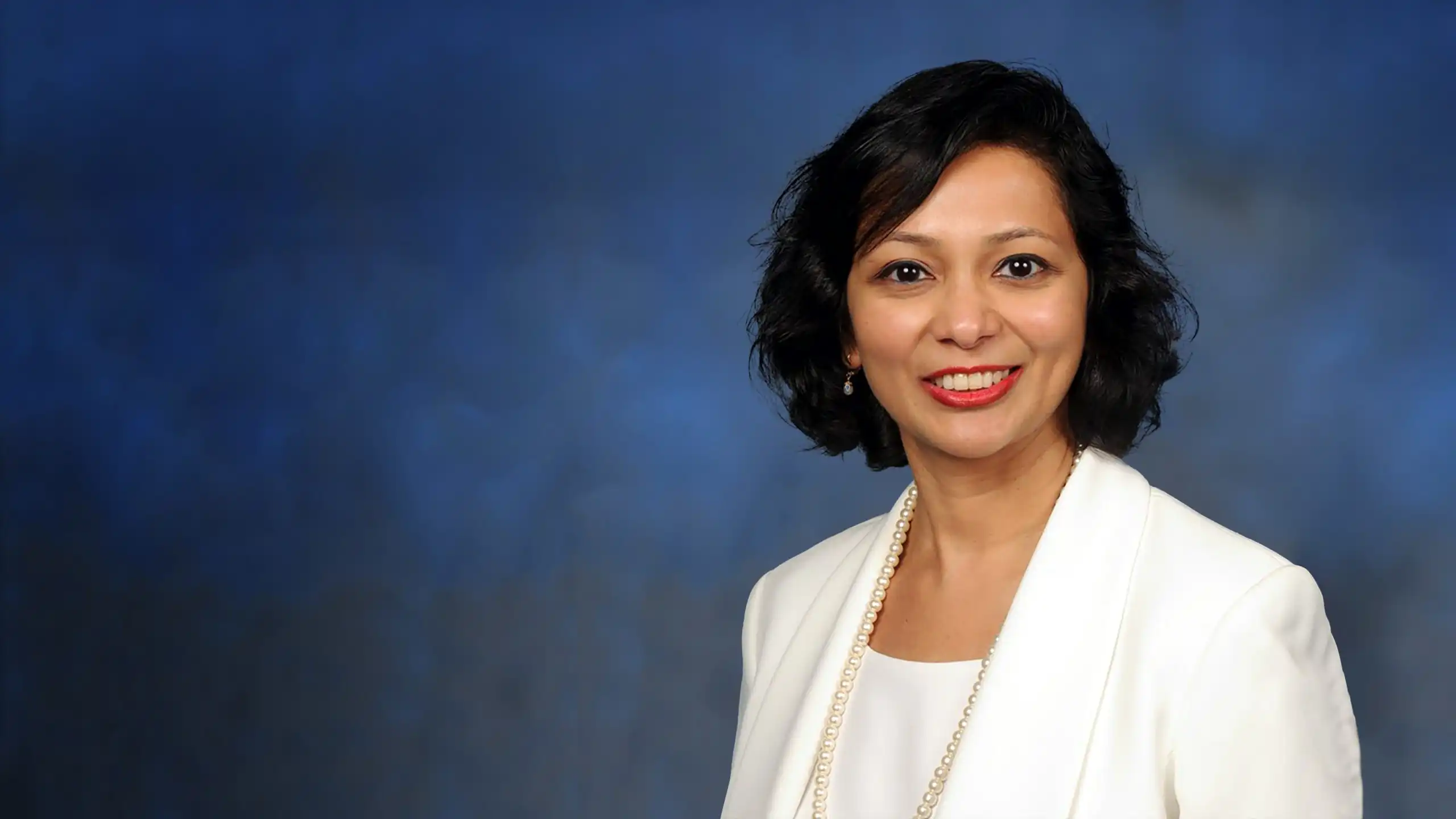 A headshot of Prajakta Mohile standing in front of a blue background.