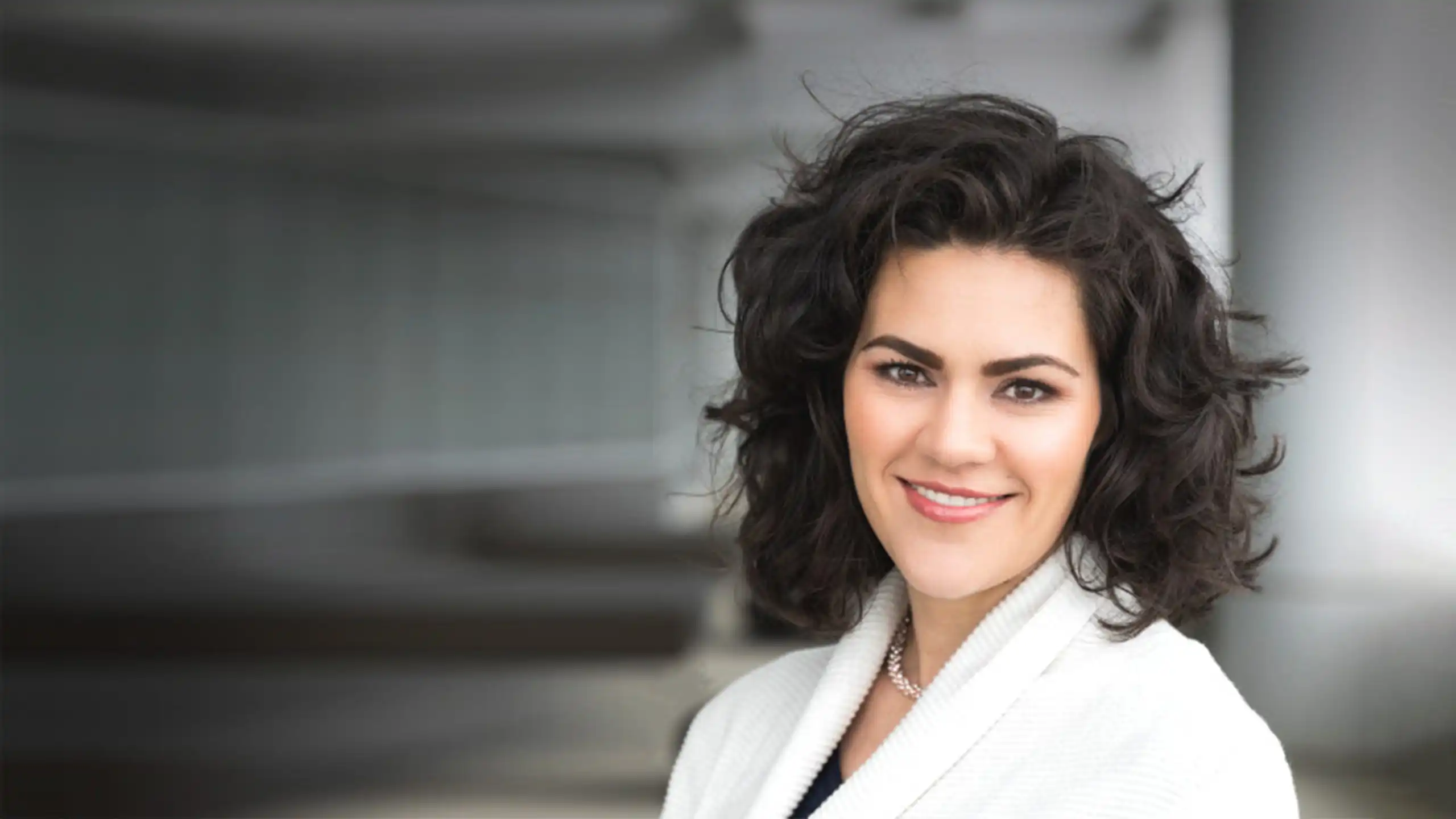 A headshot of Anne Moorer standing in front of a glass wall.