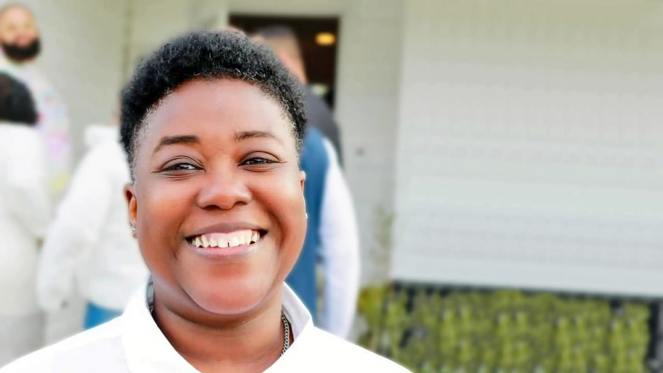 A headshot of Tammy Montgomery standing outside of a white building.