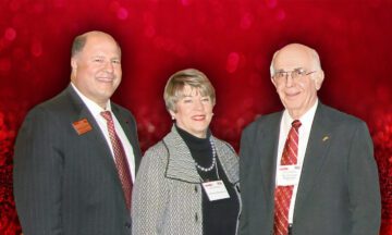 Dick Franklin, Wanda Franklin and Dick Bernhard standing in front of a red background