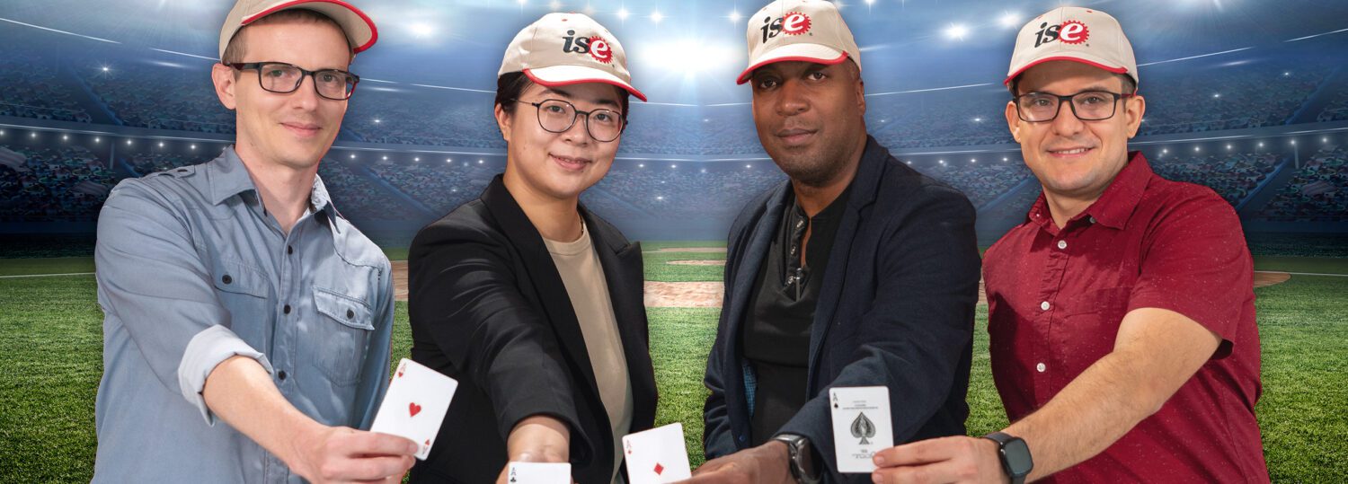 ISE new faculty members Jordan Kern, April Yu, Fred Livingston and Adolfo Escebedo standing in the outfield of a baseball stadium each holding an ace card.