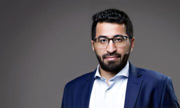 A headshot of Hassan Almuzel in front of a gray background