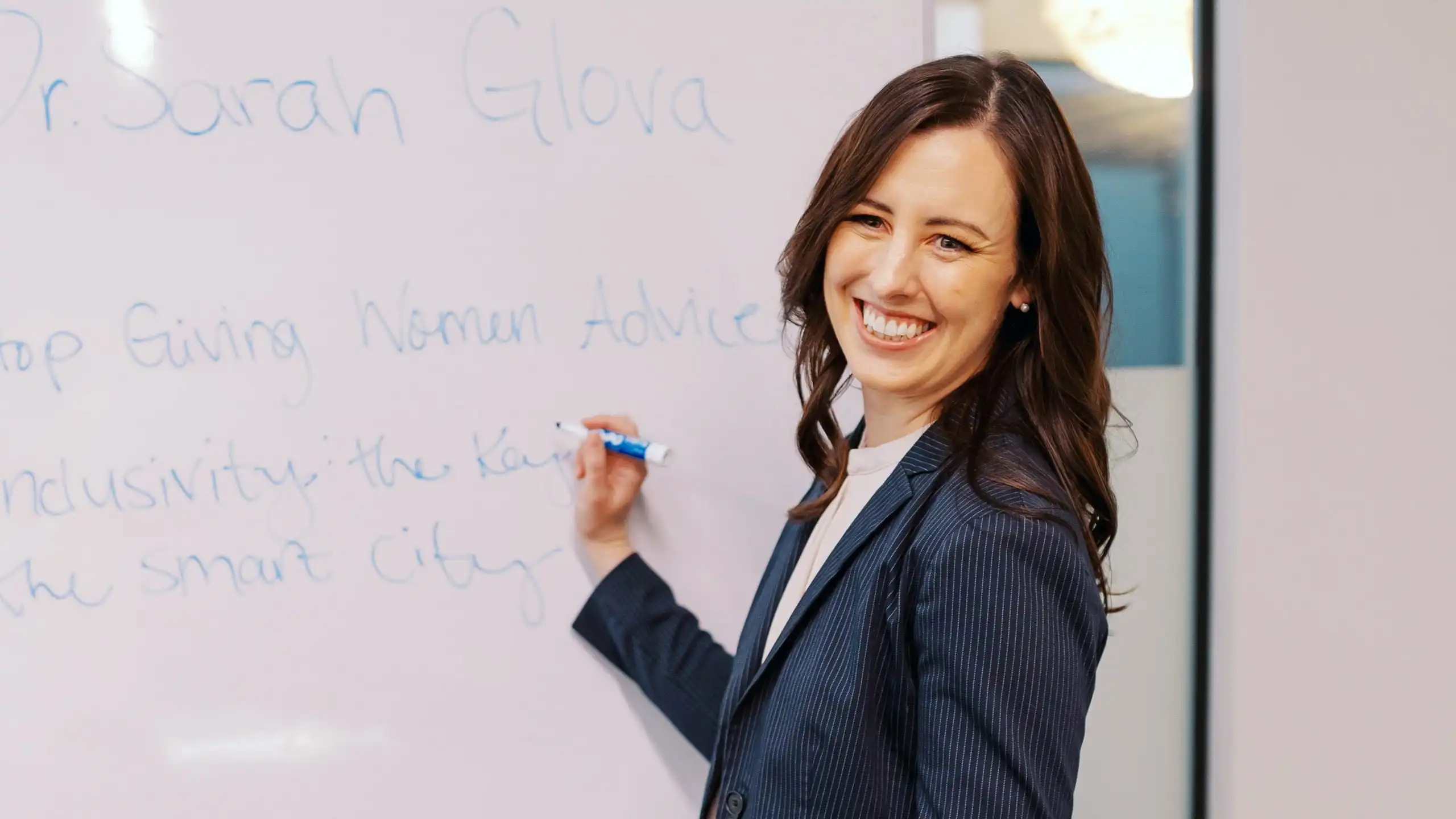 Sarah Glova writing on a whiteboard with a dry erase marker.