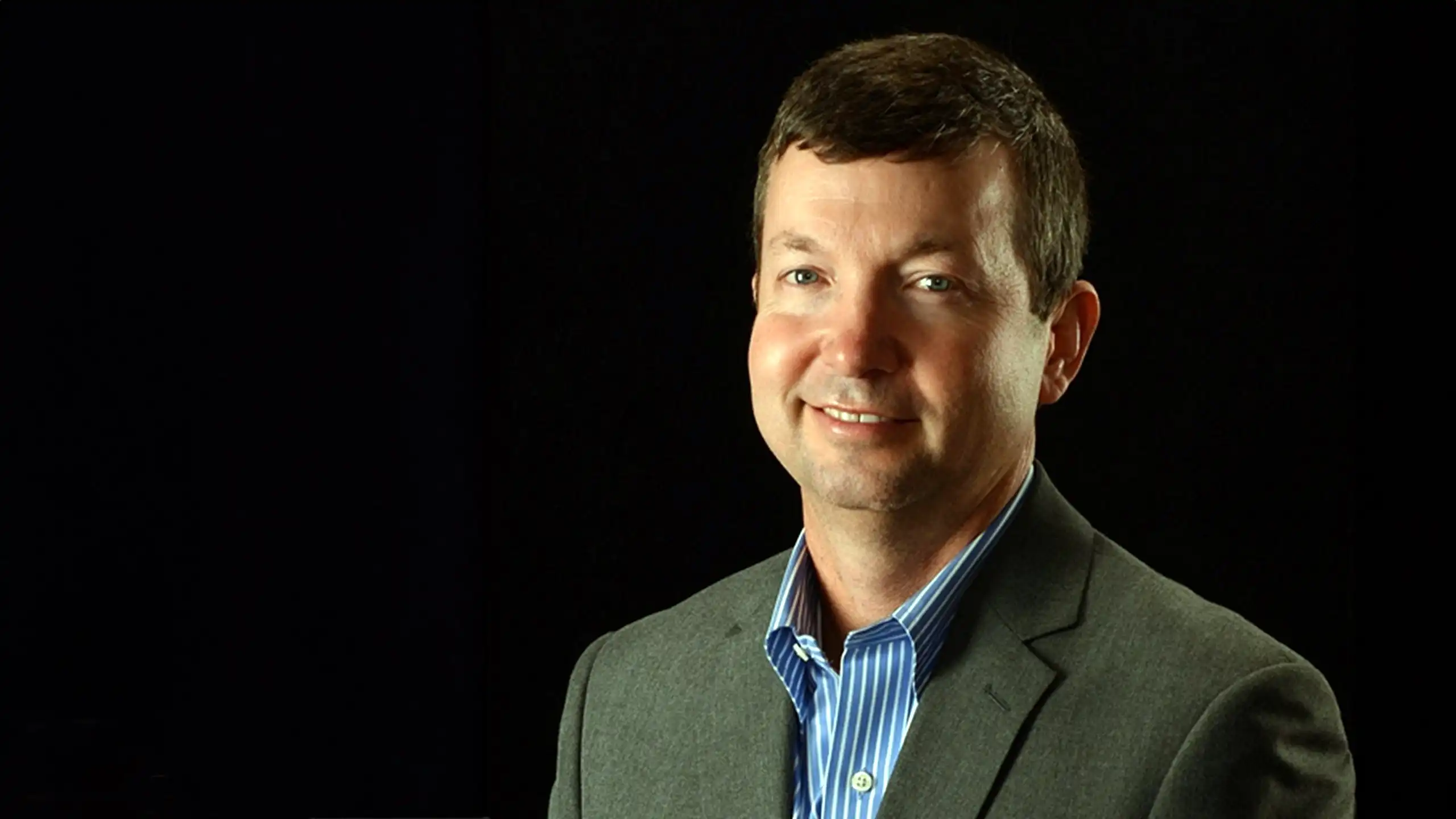 A headshot of Scott Burleson in front of a black background.