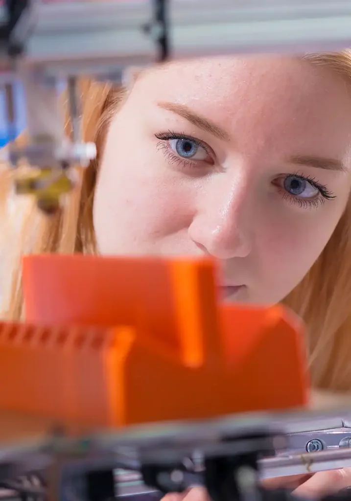 A student using a 3D printer in an advanced manufacturing class as part of their Master of Engineering Management at NC State University.