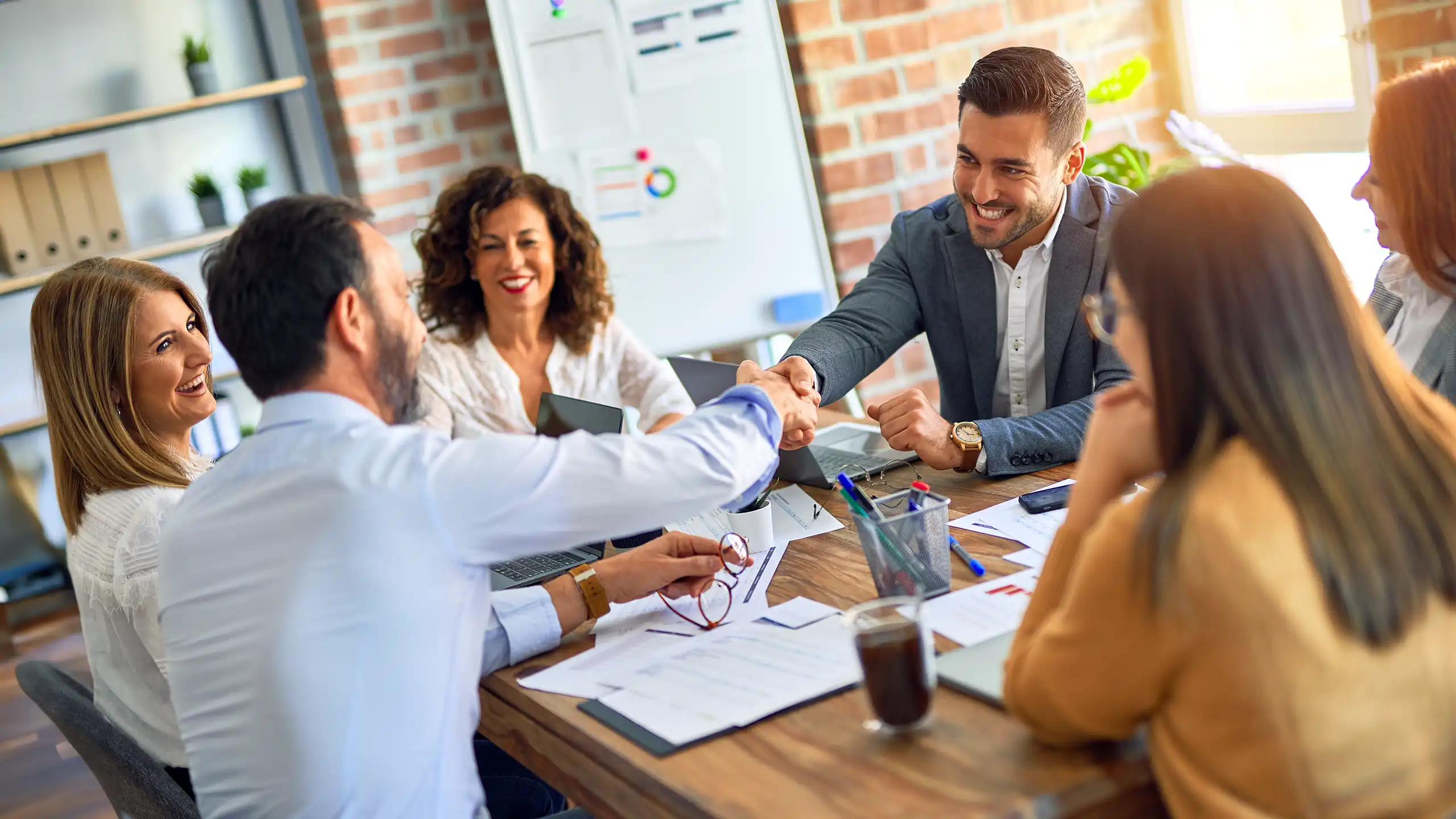 A MEM student shaking hands with a group of industry partners at a table in an office.