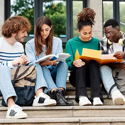 Four on-campus students sitting on the steps outside of a large building after their on-campus engineering classes.