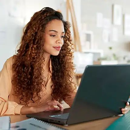 A student sitting at a laptop working on their online Master of Engineering Management degree.