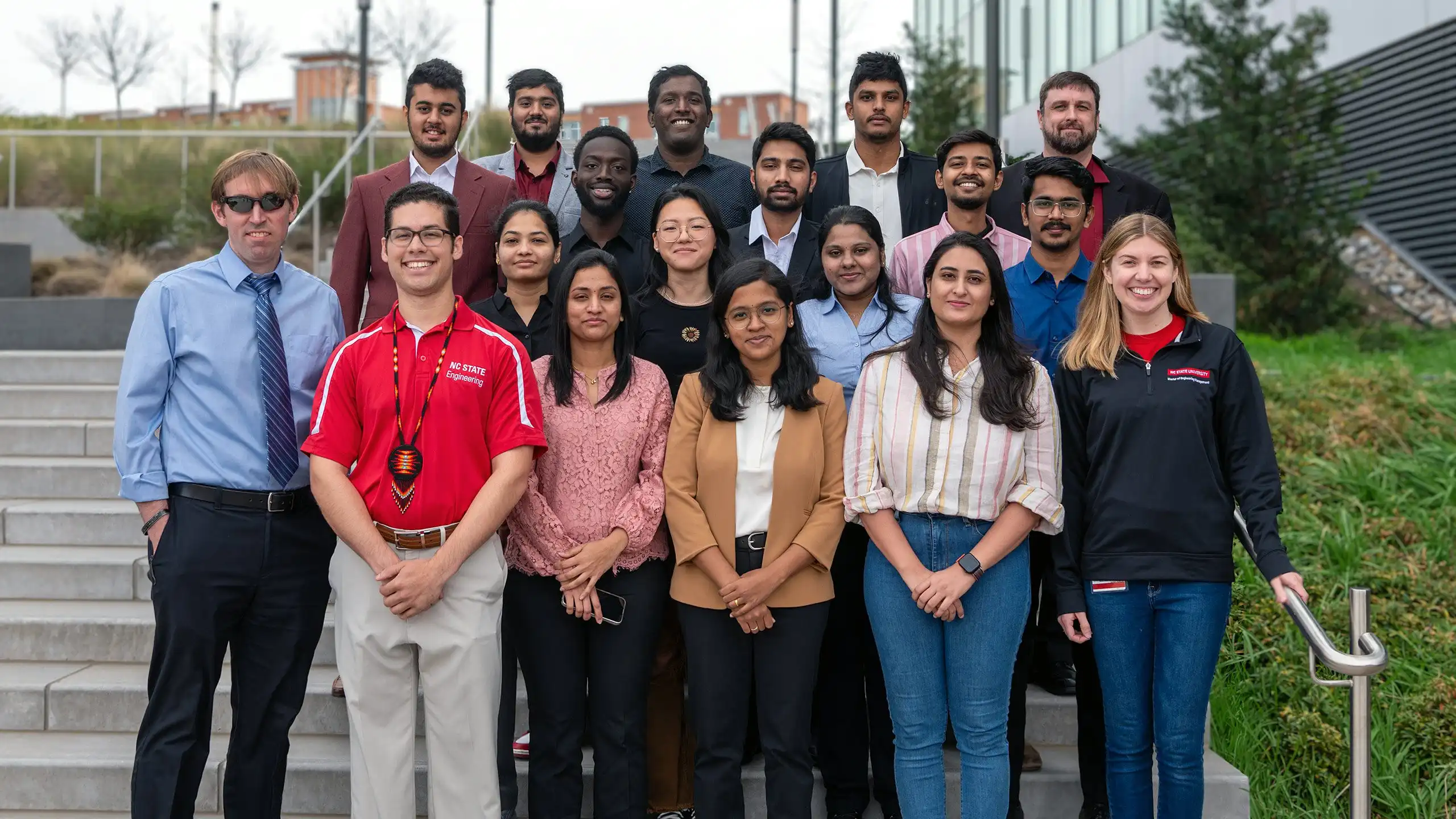 A large group of MEM students and the leadership team standing on the stairs outside of Fitts-Woolard-Hall on NC state's Centennial Campus.