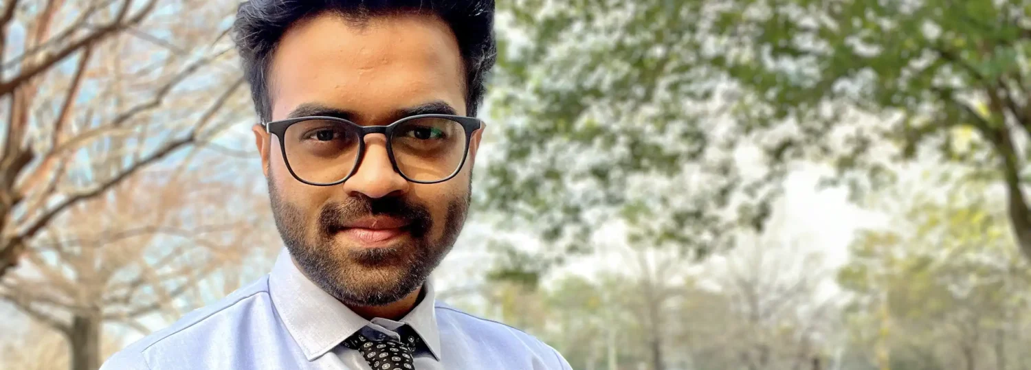 A headshot of Pavan Balekundri standing outside in front of a bunch of large trees.