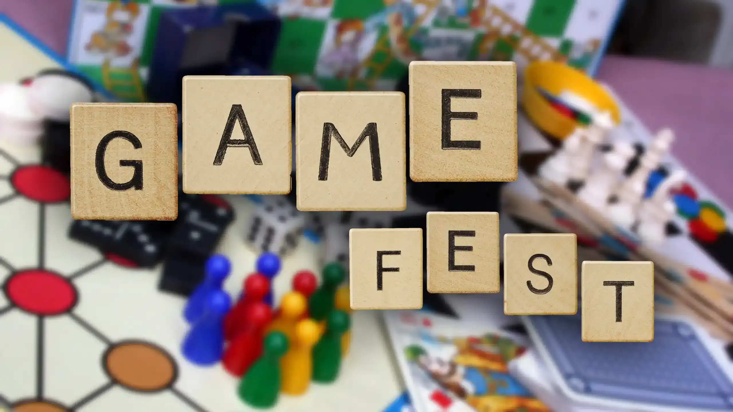 The words Game Fest spelled in Scrabble tiles floating over a background of game boards and pieces.