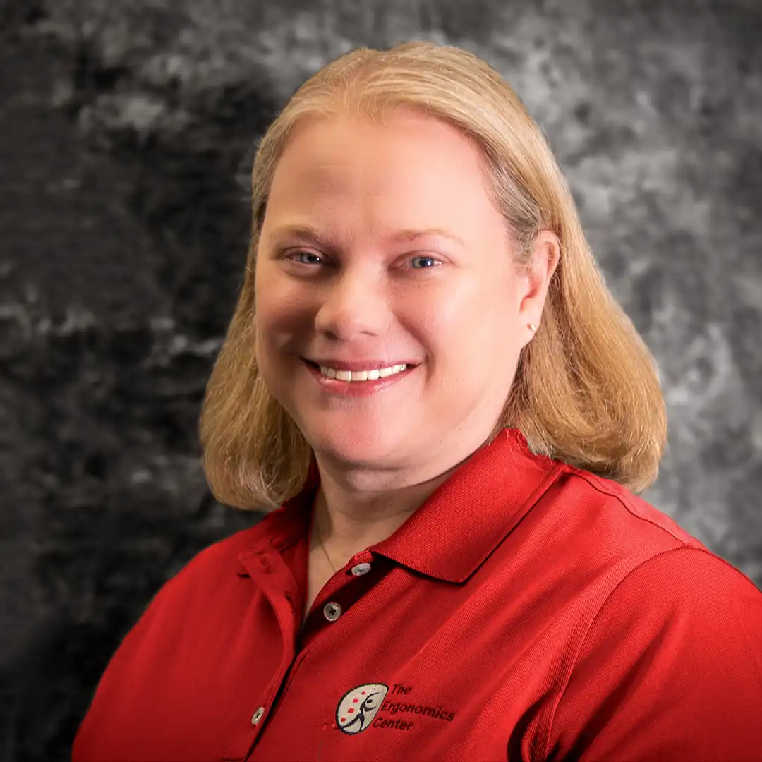 A headshot of Julia Abate standing in front of a gray-marbled background.