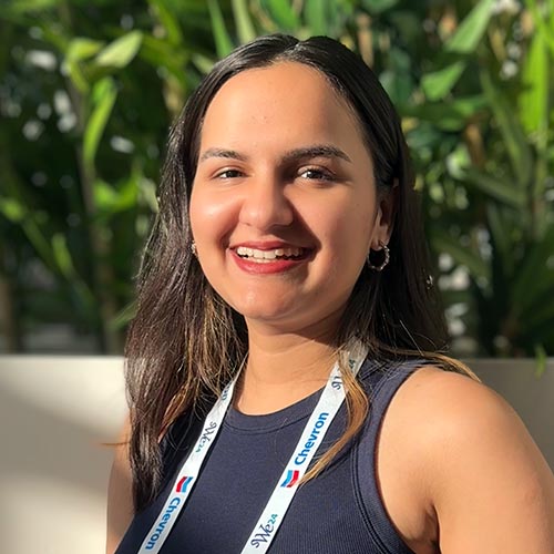 A headshot of MEMtor Tanvi Pongde standing outside in a wall of plants.