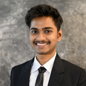 A headshot of Ayush Kohadestanding in front of a light gray, marbled background.