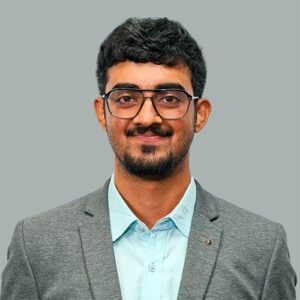 A headshot of Sandeep Vangara standing in front of a gray background.