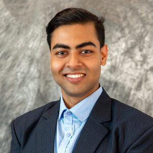 A headshot of Saumitra Ranjan standing in front of a light gray, marbled background.