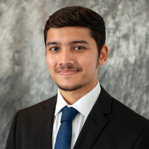 A headshot of Shubham Negi standing in front of a light gray, marbled background.