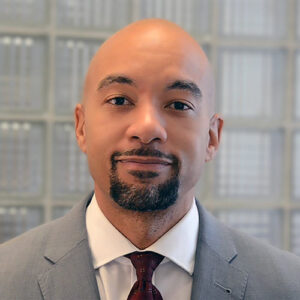 A headshot of Kanton Reynolds standing in front of a glass brick wall