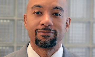 A headshot of Kanton Reynolds standing in front of a glass brick wall