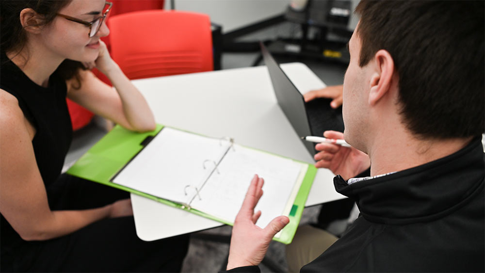 Paul Witmer help a fellow student understand a math problem while they study together.
