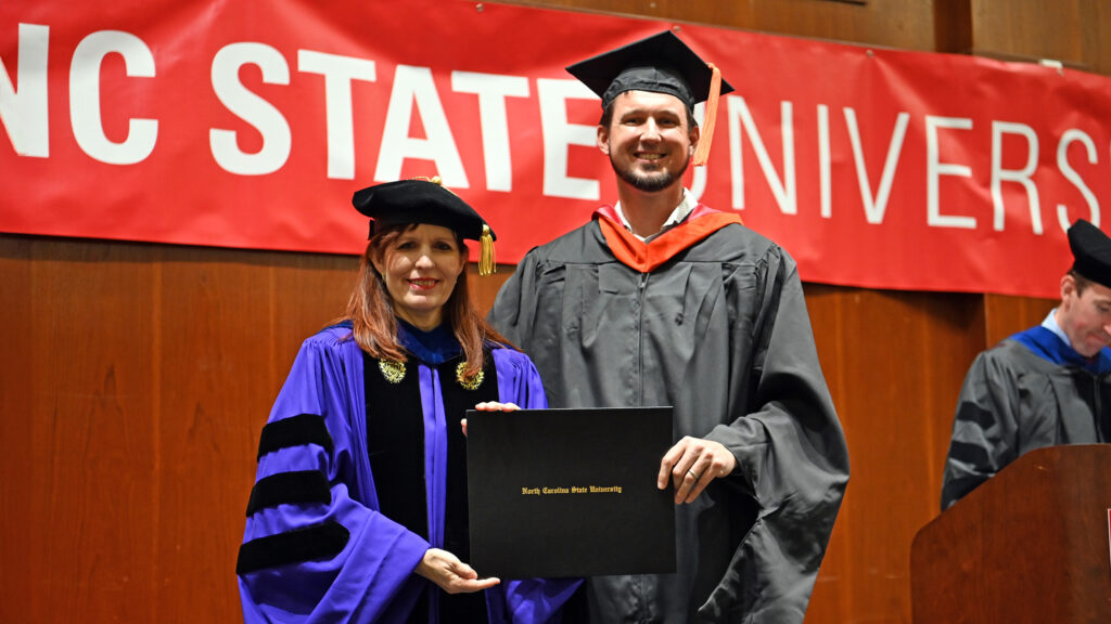Luke Phelps poses with Julie Swann and his degree