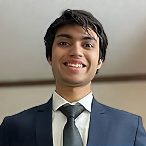 A headshot of Deval Gandhi standing in front of a white wall.